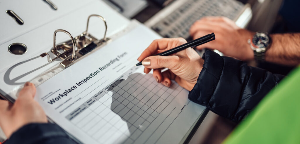 Person writing in a chart on a clipboard.