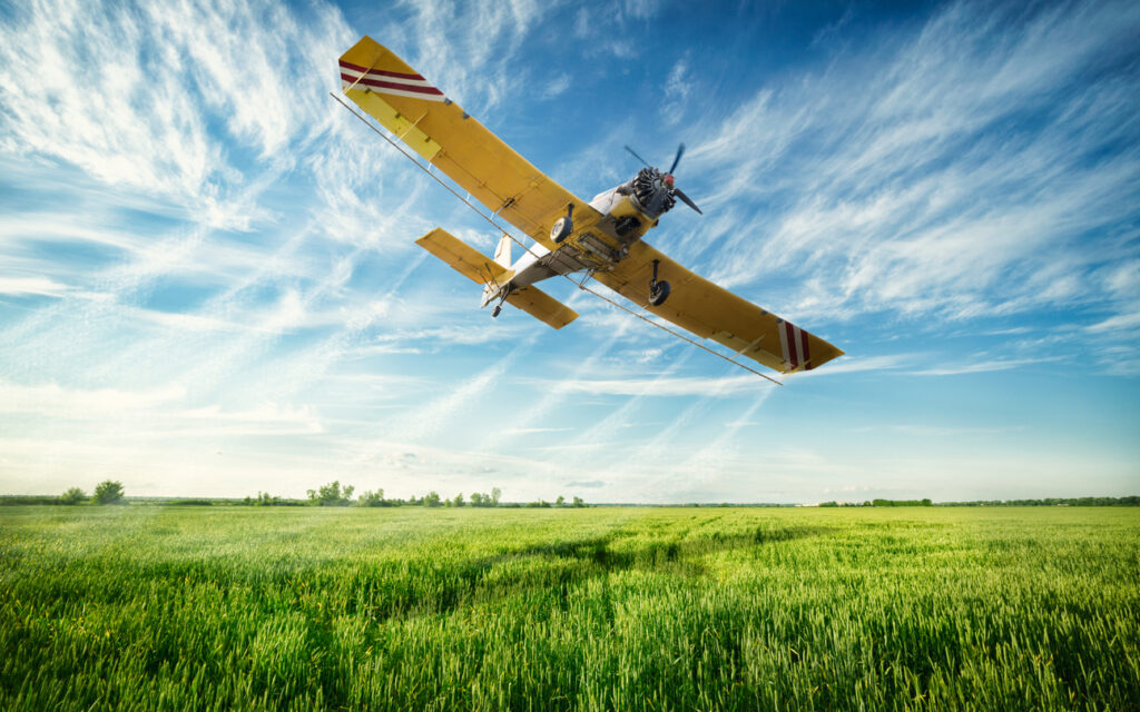 Low flying yellow plane sprayed crops in the field