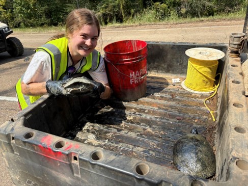 Woman puts a turtle into the back of an ATV
