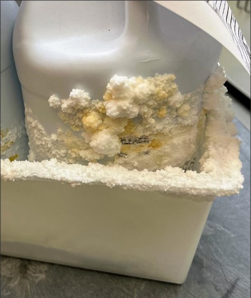large bottle in a tub covered with white, crusty material.