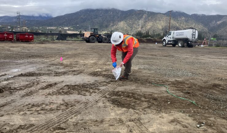 Worker collects sample of soil