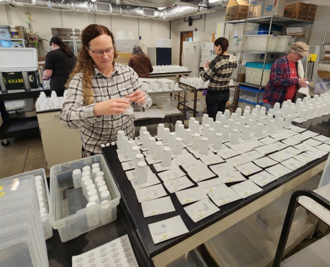 People in a lab with water samples spread across tables.