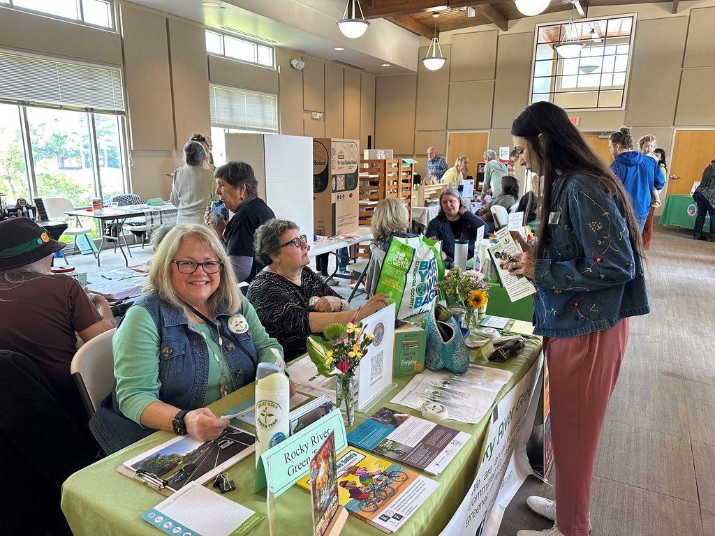 Several women sit at tables in an exhibit hall