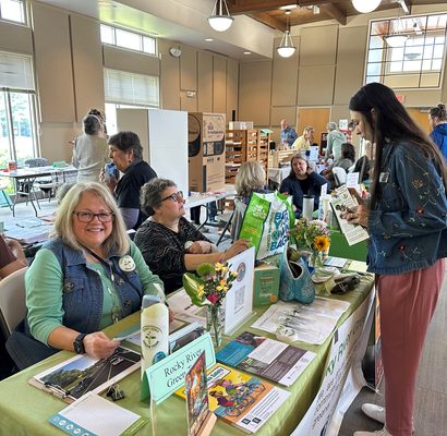 Several women sit at tables in an exhibit hall