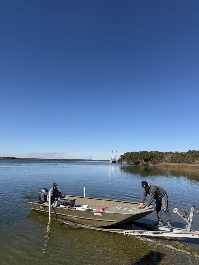 One person pushes the boat off the trailer while another steers from within the boat.